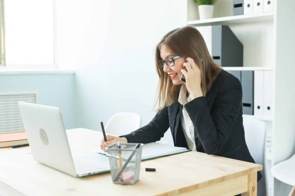 Business, realtor and people concept - Attractive woman in office talking on phone and make notes